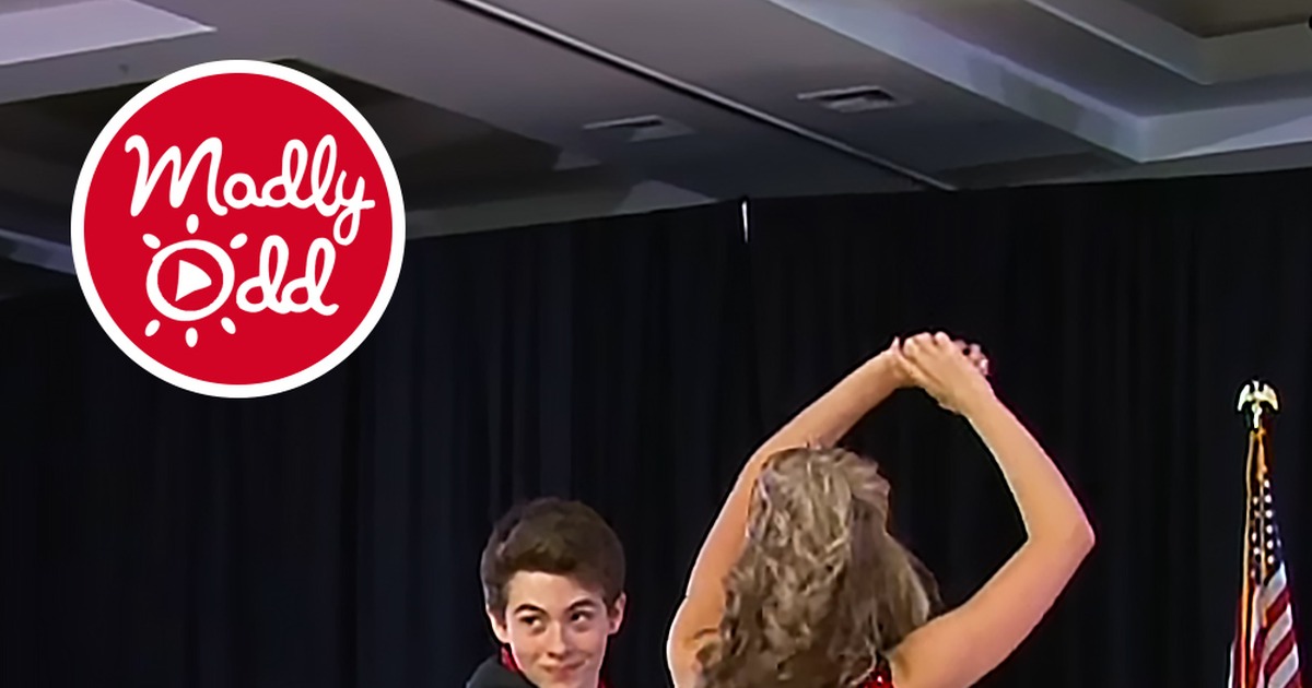 Teen swing dancers in red and black outfits perform a dazzling routine on a dance floor.