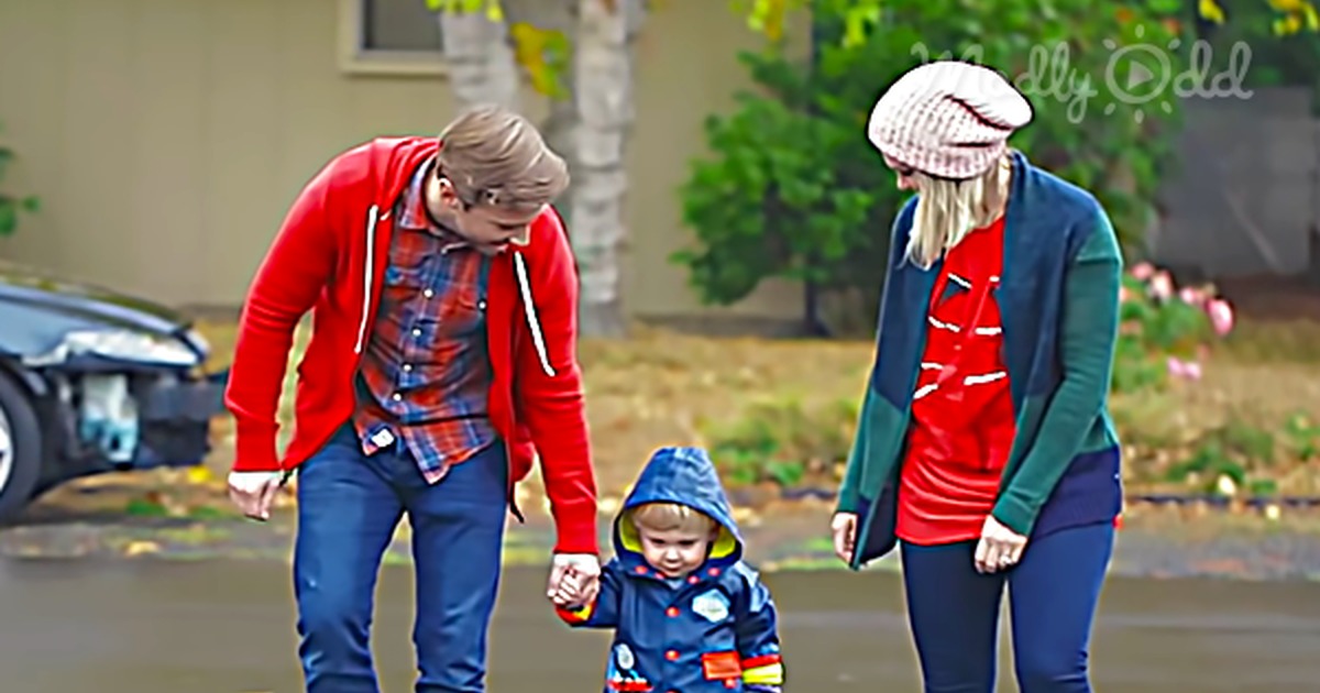 A family walks together, holding hands, with a child carrying a bag, in a suburban setting.