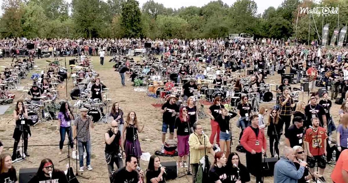 Hundreds of drummers, bassists, and singers perform ‘We Will Rock You’