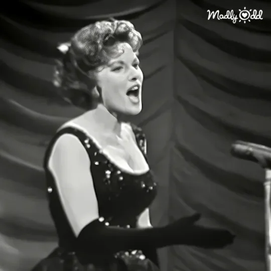 1961 crowd watches Maureen O'Hara perform 'Hello Young Lovers,' faces filled with admiration.