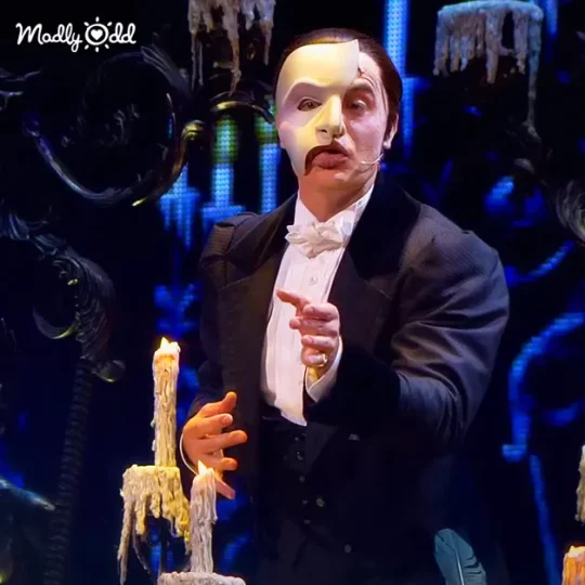 Phantom songs performed, singer in costume, dramatic lighting enhancing the scene.