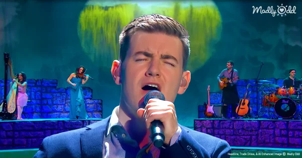 Emmet Cahill from Celtic Thunder on stage and singing an old Irish ditty, mouth open and holding a mic while he is singing.