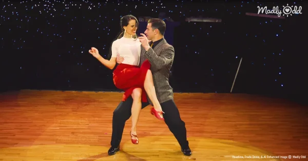 Swing dancers on dancefloor. Girl is wearing red skirt. Man is holding her in the spotlight.