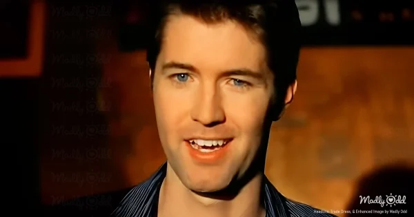 A dimly lit stage with Josh Turner front and center, his cowboy hat casting a shadow over his eyes. The backdrop is rustic, with a single spotlight emphasizing his deep, mournful expression as he strums his guitar.