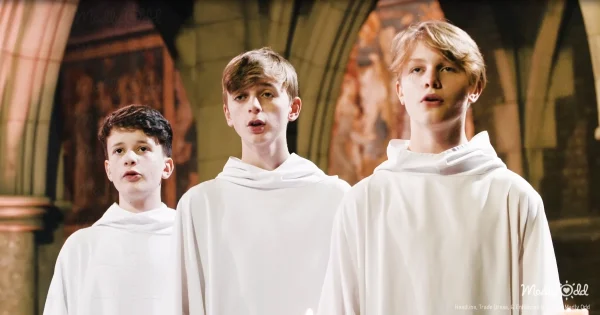 A serene choir of boys dressed in white robes performing “Carol of the Bells” in a grand cathedral. Ethereal light streams through stained-glass windows, casting vibrant patterns on the stone walls as their angelic voices fill the space.